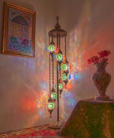 an ornate light fixture in front of a wall with colorful lights on it and a vase filled with flowers