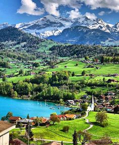 a scenic view of mountains, lakes and houses in the foreground with snow capped mountains in the background