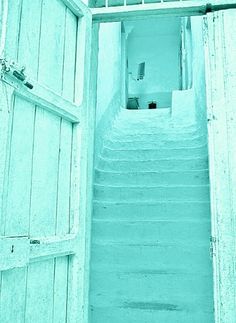 an open door leading to a stairway with white walls and blue shutters on either side