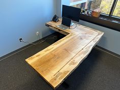 an office desk made out of wood with a laptop on it and a window in the background