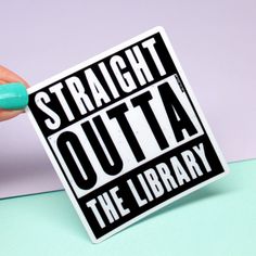 a hand holding a sticker that says straight outa the library