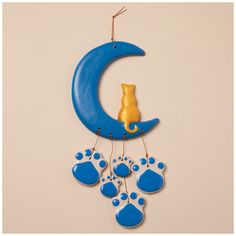 a blue and yellow cat on the moon with paw prints hanging from it's side