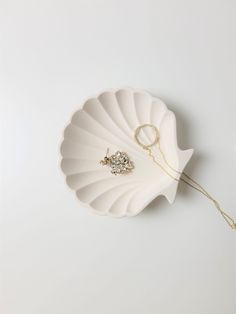 a white shell with a gold chain attached to it and a diamond brooch in the center