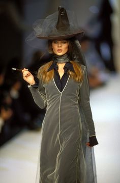 a woman in a witch costume is walking down the runway with her hat and wand