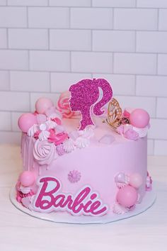 a pink cake decorated with an elephant and name on it's icing is sitting on a table