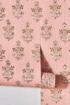 a pink wallpaper with small flowers and leaves on it's side, next to a pair of scissors