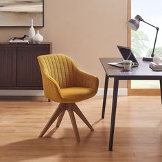 a yellow chair sitting in front of a laptop computer on top of a wooden table