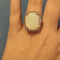 an opal and diamond ring on someone's hand