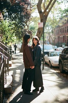 two women are standing on the sidewalk talking