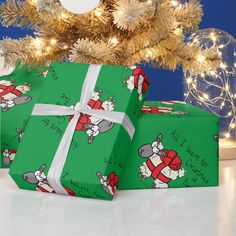 two presents wrapped in green wrapping paper under a christmas tree