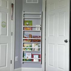 a white book shelf sitting in the corner of a room next to an open door