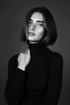 a woman with long hair is posing for a black and white photo wearing a turtle neck sweater