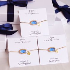 three bracelets with blue stones on them sitting in front of two white gift boxes