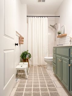 a white bathroom with green cabinets and a beige rug on the floor in front of it