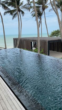 an outdoor swimming pool surrounded by palm trees and the water running down it's sides