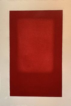 a red square in a white frame on the wall