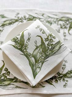 a white plate topped with a napkin covered in green floral designs on top of a table