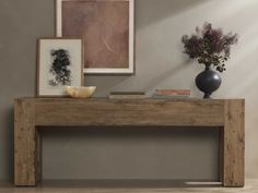 a wooden table with two vases on top of it next to pictures and paintings