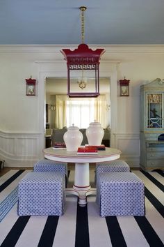 a dining room table with blue and white striped rugs on the floor next to it