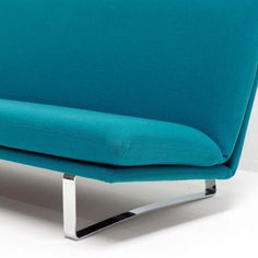 a blue couch sitting on top of a white floor next to a metal leg rest