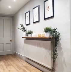 three framed pictures hang on the wall above a radiator in a white room