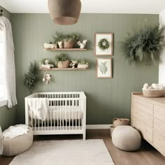 a baby's room with green walls, white crib and potted plants