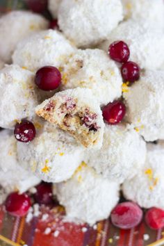 cranberry and orange snowball cookies are piled on a plate with powdered sugar