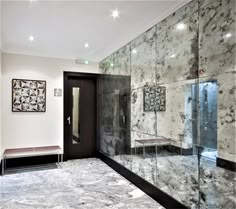 a bathroom with marble walls and flooring in the shower area, along with a bench