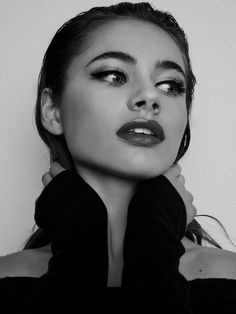 black and white photograph of a woman with her hands on her neck, wearing a scarf