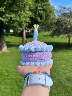 a hand holding a knitted hat in the grass