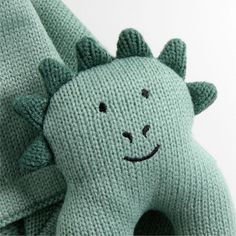 a green knitted toy with a smiling face on it's back and arms