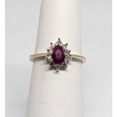 a diamond and ruby ring set in yellow gold with diamonds on the band, setting on a white napkin