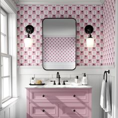 a bathroom with pink vanity, mirror and wallpaper in it's design style