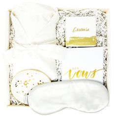 an open box with white and gold items including a mask, napkins, and other items