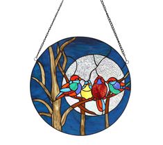 a stained glass window with three birds sitting on a tree branch in front of the moon