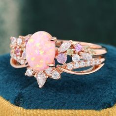 an opal and diamond ring sits on top of a blue velvet cushion