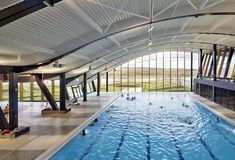 an indoor swimming pool with people in it and large windows on the side of the building