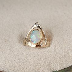 Stunning ring featuring a bezel-set opal on a wide, organically shaped band, adorned with a crown-like V-shaped band encircling the opal and embellished with glistening diamond accents Celestial 14k Gold Opal Wedding Ring, Celestial Yellow Gold Opal Ring, 14k Gold Celestial Opal Ring, Luxury Celestial Opal Ring, Luxury Gold Opal Ring With Polished Finish, Visual Board, Ring Opal, Custom Ring Designs, Ocean Conservation