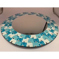 a round mirror with blue and white tiles on the bottom is sitting on a table