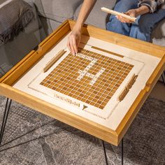 a person sitting on a couch with a wooden tray holding a piece of art that has been cut into squares