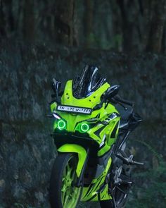 a neon green motorcycle parked in front of a rock wall with its lights on at night