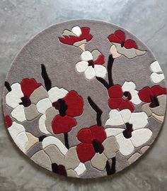 a round rug with red, white and grey flowers on the bottom is shown in front of a gray background