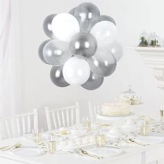 a white table topped with lots of silver and white balloons