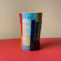 a multicolored vase sitting on top of a red table