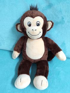 a brown and white stuffed monkey sitting on top of a blue blanket with eyes wide open