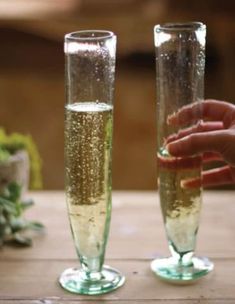 two champagne flutes are sitting on a table, one is filled with liquid and the other has gold flecks