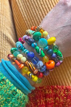 a person wearing colorful bracelets on their wrist and holding onto one another's arm