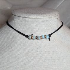 a necklace on a mannequin neck with beads and leather cord in the shape of rectangles