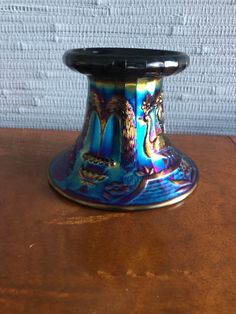 a blue and black vase sitting on top of a wooden table next to a brick wall