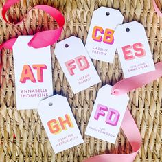 four tags with pink ribbons are on a wicker basket